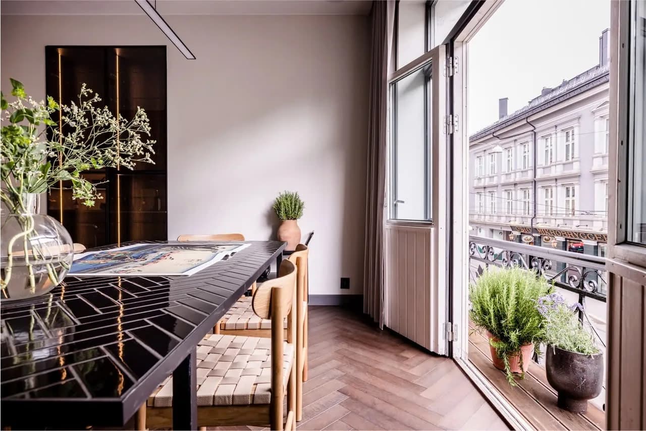 Spisestue med åpen balkongdør og planter i morgensol