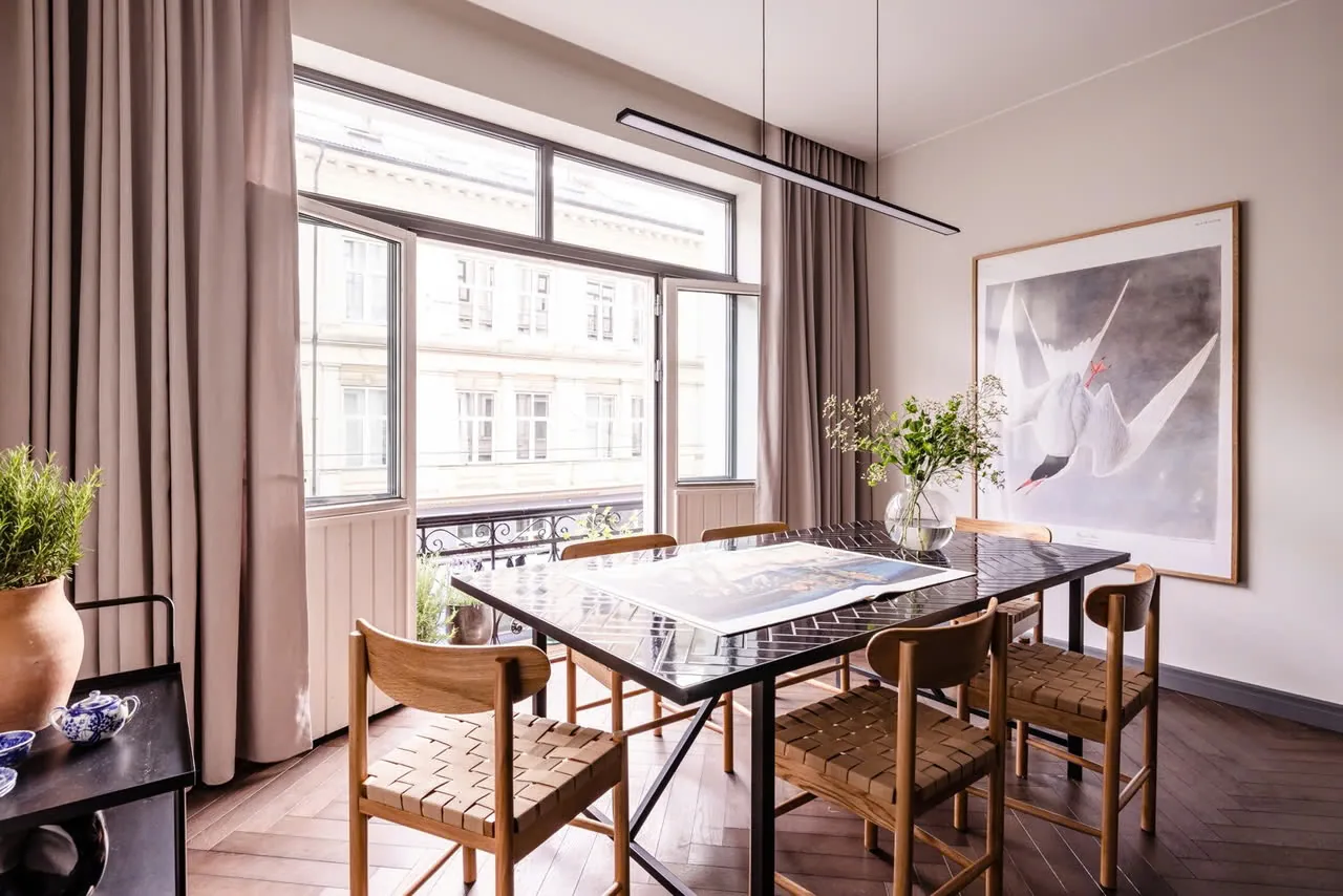 Spisestue med langbord, flettede stoler og maleri på veggen